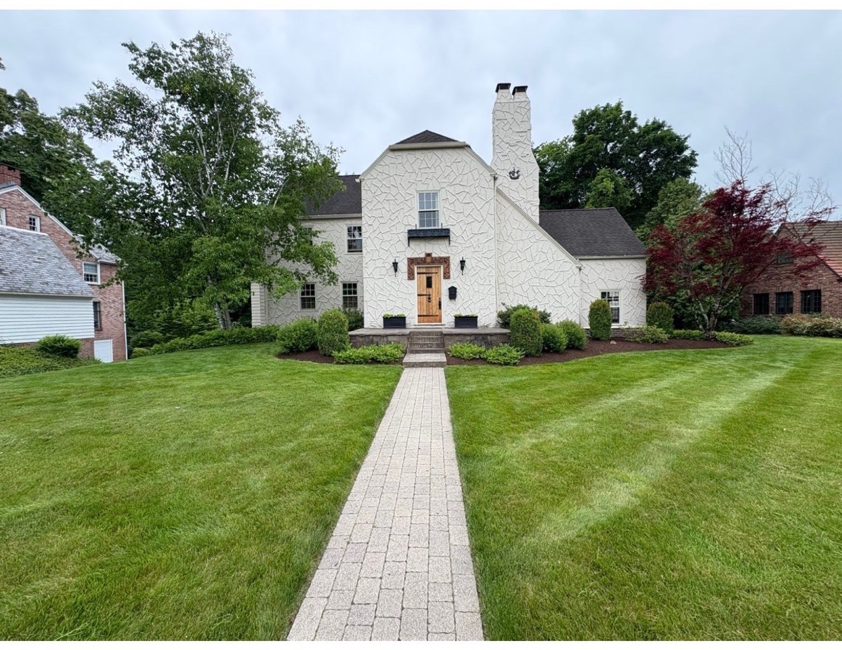 Tudor-style home with paver walkway and clean lawn